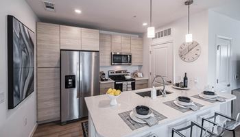 A kitchen with a large island and a stainless steel refrigerator